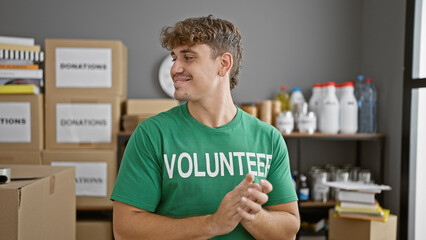 Handsome young hispanic man volunteering at a charity center, confidently clapping and smiling in...