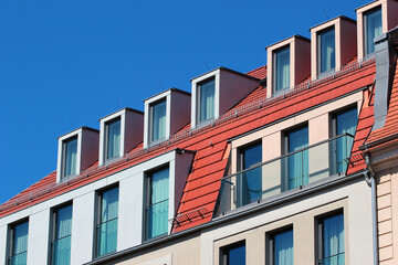 Modern attic windows on red roofs against blue sky background