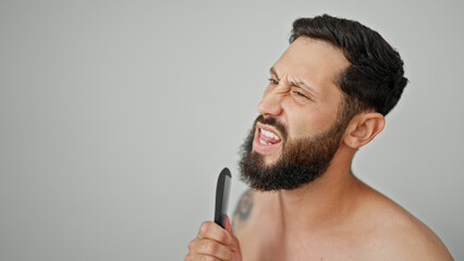Young hispanic man singing song using comb as a microphone over isolated white background