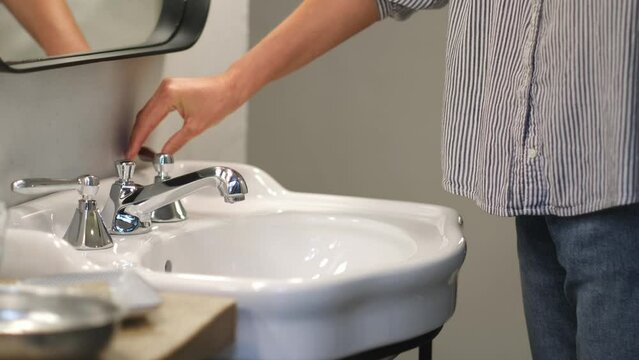 Young woman turn off water tap after hygienic procedures