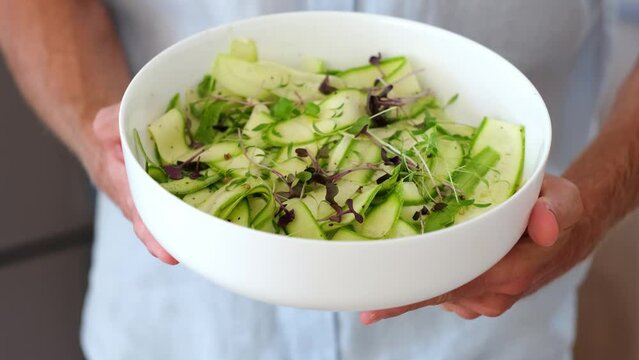 Man holding bowl alternative vegetable homemade zucchini pasta salad. Zoodle 