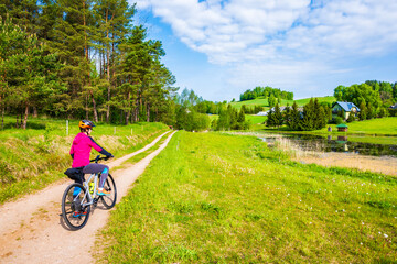 Woman cyclist on gravel road near Postawele village , Suwalki Landscape Park, Podlasie, Poland