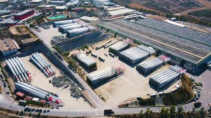 Wind turbine blades ready for shipping and installation. Manufacturing company of windmill parts. Aerial establishing shot