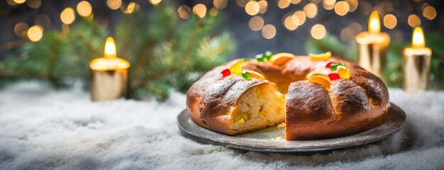 A traditional Rosca de Reyes cake rests on a snowy table, adorned with candied fruits, celebrating...