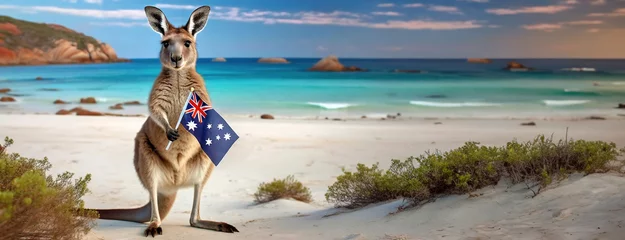 Foto auf Acrylglas Antireflex A kangaroo stands on a serene beach, holding the Australian flag, Australia Day concept. Pride of a nation with its iconic wildlife and stunning coastal landscape bathed in the light of dawn. © vidoc