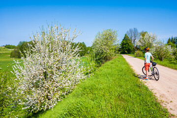 Woman cyclist on gravel road during spring in Suwalki Landscape Park, Podlasie, Poland