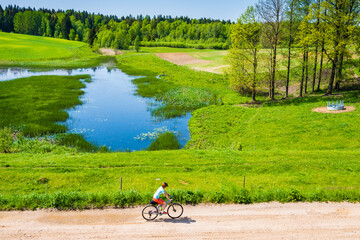 Woman cyclist riding on gravel road during spring in Suwalki Landscape Park, Podlasie, Poland - 691166528