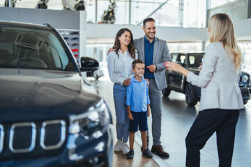 Happy family came to a successful agreement with salesperson while buying a car in a showroom....