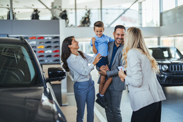Happy family choosing new car, salesman showing them luxury auto at automobile dealership store. Customers selecting vehicle, consulting manager at modern showroom shop - obrazy, fototapety, plakaty