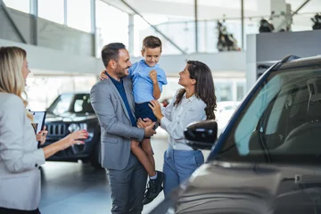 Foto op Canvas Family in a car dealership. Happy family came to an agreement with a car salesperson at a meeting in a showroom. Happy family choosing a new car in a showroom © Dragana Gordic