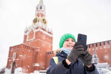 a child, a boy, a schoolboy takes a photo, a selfie near the Kremlin on Red Square in Moscow,...