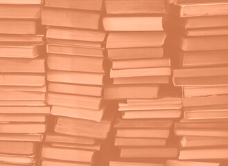 Peach Fuzz colour chaotic stack of old books background. Background from old books that are exhibited in a chaotic manner. Colour of the year 2024. Trendy Peach Fuzz color.