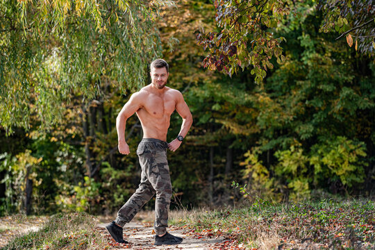Shirtless Man Exercising on a Forest Path. A shirtless man walking on a path in the woods