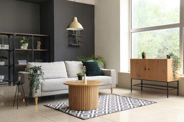 Interior of modern living room with comfortable grey sofa and wooden coffee table