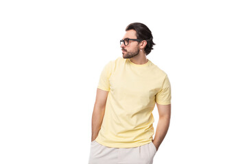 Fototapeta premium fashionable young successful European guy with stubble and mustache dressed in a light yellow T-shirt put on glasses
