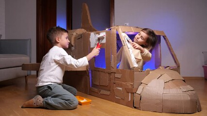children build an airplane out of cardboard. kids paint a cardboard airplane