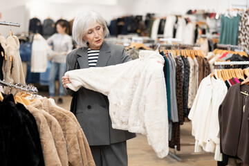Elderly woman demonstrates fur coat in a clothing boutique