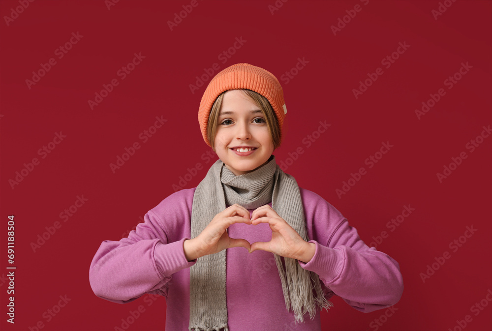 Canvas Prints cute little happy boy in winter clothes showing heart gesture on red background