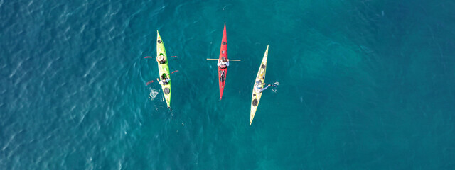 Aerial drone ultra wide photo of athletes competing with rowing in sport canoe in deep emerald...