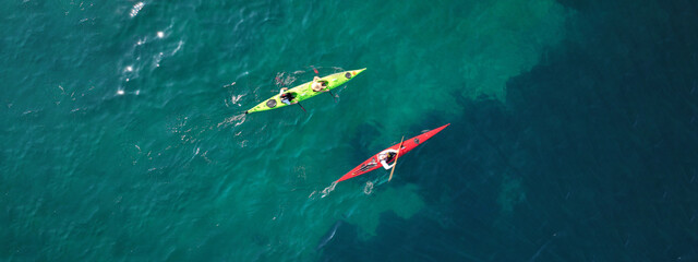 Aerial drone ultra wide photo of athletes competing with rowing in sport canoe in deep emerald...