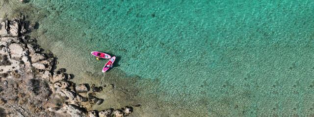 Aerial drone ultra wide panoramic photo of couple with pink SUP or Stand Up Paddle board anchored in tropical exotic bay with emerald calm sea