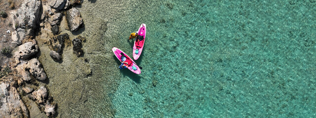 Aerial drone ultra wide panoramic photo of couple with pink SUP or Stand Up Paddle board anchored...