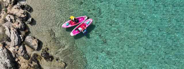 Aerial drone ultra wide panoramic photo of couple with pink SUP or Stand Up Paddle board anchored...