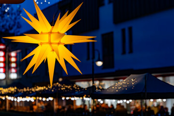 a shining christmas star in front of a christmas market