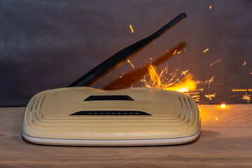 Wi-fi router burns with fire from overheating and smoke on the dark background, sparks fly when...