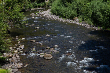 Boulder strewn river in Mount Hood Wilderness near Government Camp, Oregon on a warm summer day with green trees and rushing river