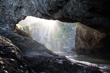 Sunbeams streaming through an arch at Secret Beach in the Samuel H. Boardman Scenic Corridor on Oregon's Adventure Coast.