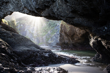 Sunbeams streaming through an arch at Secret Beach in the Samuel H. Boardman Scenic Corridor on Oregon's Adventure Coast.