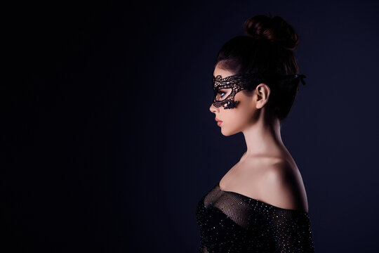 Side photo of young hot chic femme fatale role on festival wear carnival bdsm mask isolated over dark color background