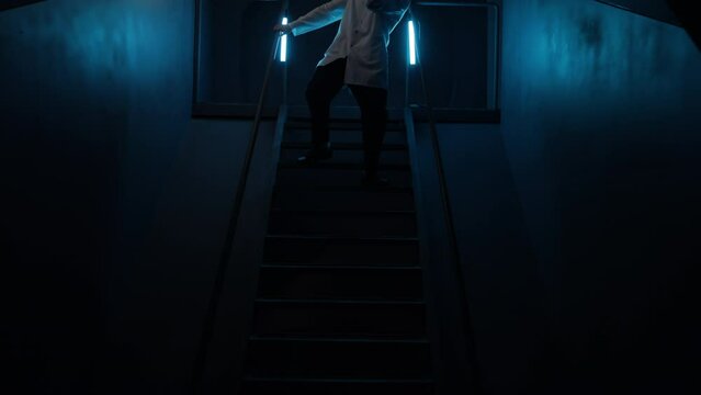 Medical worker checking underground laboratory with a flashlight in his hands. Caucasian man walking downstairs to examine suspicious noise and activity. High quality 4k footage