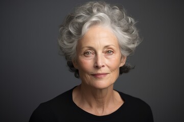 Portrait of a beautiful senior woman with grey hair against grey background