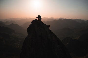 Epic scene with the silhouette of two mountaineers climbing a pinnacle in the Pyrenees backlit...