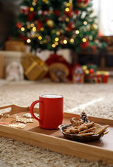 Red mug on the background of the xmas tree bokeh lights. Christmas time, New Year holiday.