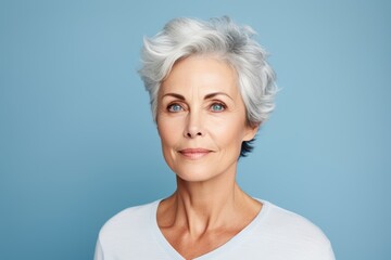 Mature woman with grey hair. Portrait of beautiful mature woman looking at camera and smiling while standing against blue background