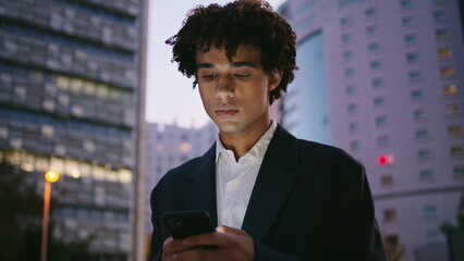 Serious business man working cellphone at sunset street portrait. Guy texting