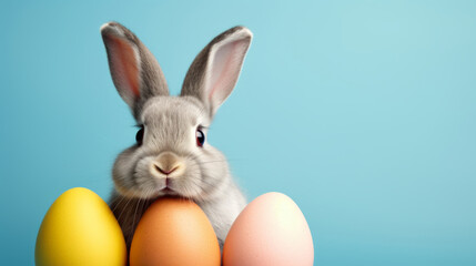 Fototapeta na wymiar Ein Hase mit farbigen Eiern auf türkisem Hintergrund.