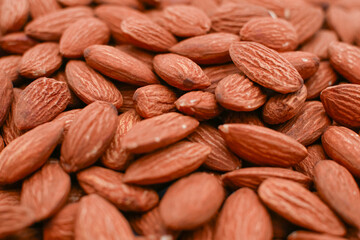 A pile of raw almonds, The almonds are brown and have a rough texture. They are a healthy snack or addition to a meal.
