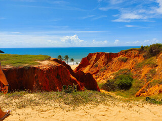 A beach with a green hill and a blue sky