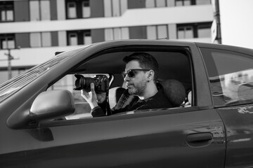 Naklejka premium Black and white image of undercover agent taking pictures from the car 