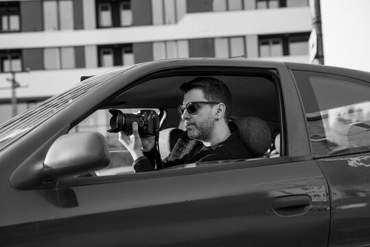 Black and white image of undercover agent taking pictures from the car 
