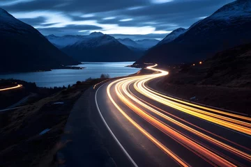 Fototapeten a highway road with cars moving fast with motion blur between snowy mountains © DailyLifeImages