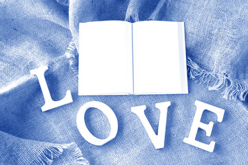 見開きの本とLOVEの文字（白い本と文字と青の背景、ジュートの背景）