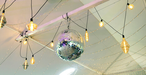 Disco ball. A mirrored ball on the ceiling that reflects colored light in the club.