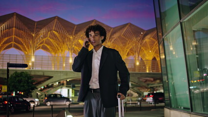 Young man talking phone at illuminated city. Smiling businessman waving arm