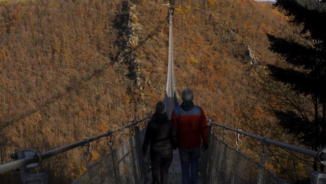Couple walking in Geierlay suspension bridge during autumn, in Germany