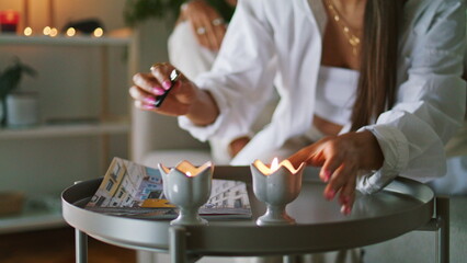 Woman hands lighting candles home closeup. Cute newlyweds laying under blanket